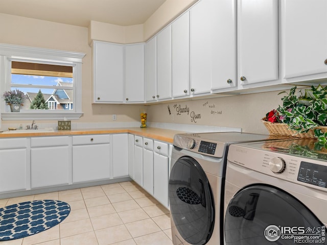 laundry room featuring a sink, cabinet space, light tile patterned floors, and washing machine and clothes dryer