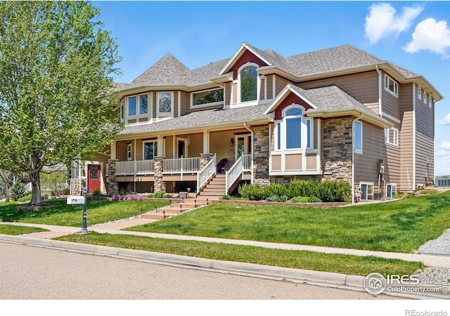 3916 Fowler Ln, Longmont, CO 80503 - view of front facade with stone siding, a porch, a front lawn, and roof with shingles