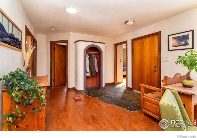 entryway with baseboards, arched walkways, and dark wood-style floors