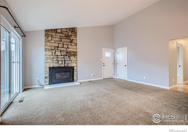 unfurnished living room featuring visible vents, high vaulted ceiling, carpet, a stone fireplace, and baseboards