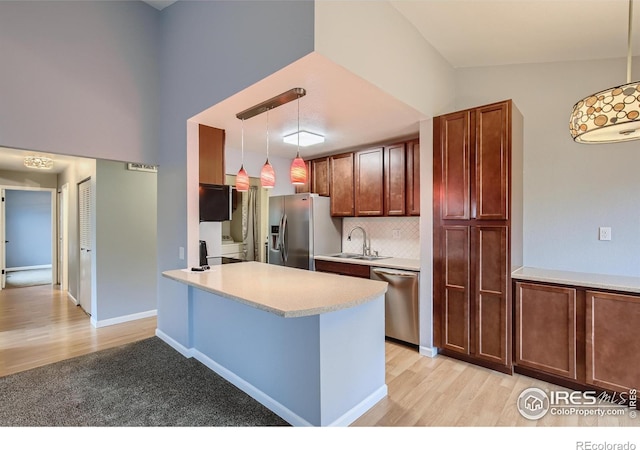 kitchen featuring pendant lighting, a sink, tasteful backsplash, appliances with stainless steel finishes, and light countertops