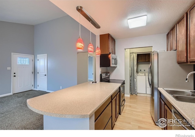 kitchen with decorative light fixtures, washer and clothes dryer, stainless steel appliances, a textured ceiling, and a sink