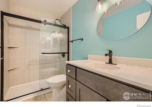 full bath with vanity, tile patterned floors, toilet, and a stall shower