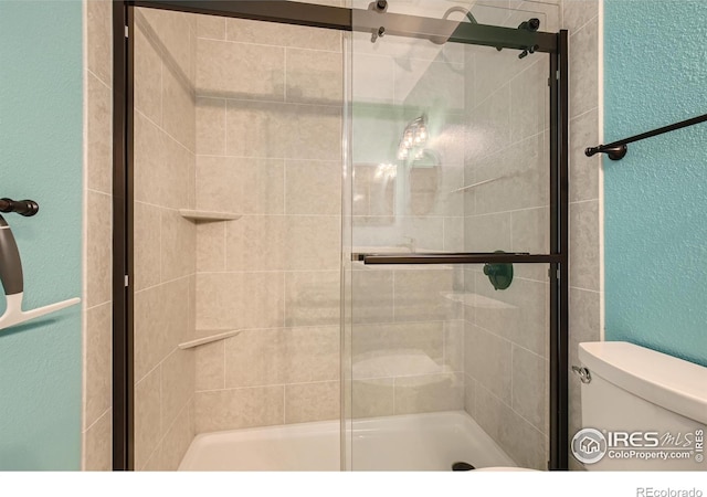 full bathroom with a shower stall, toilet, and a textured wall