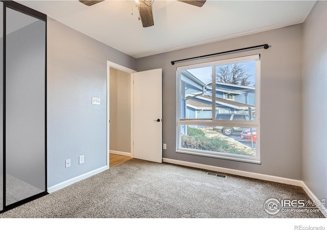 spare room with a ceiling fan, visible vents, baseboards, and carpet floors