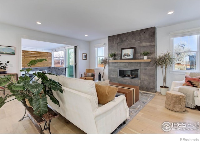 living room featuring recessed lighting, a tile fireplace, and wood finished floors