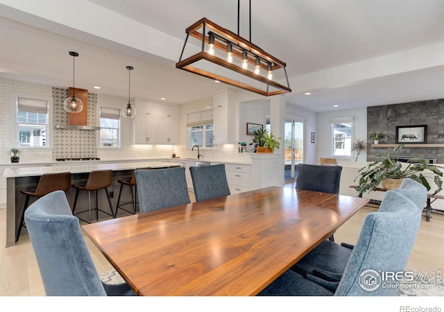 dining space featuring light wood-style flooring, recessed lighting, and a tile fireplace