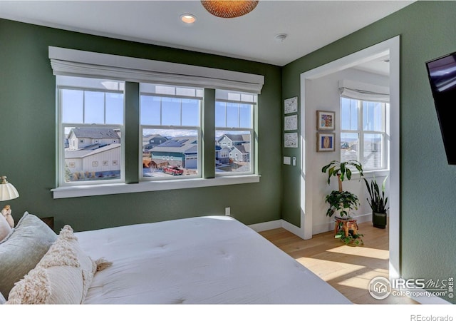 bedroom with recessed lighting, multiple windows, wood finished floors, and baseboards