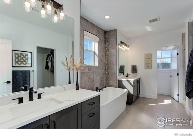 bathroom with a sink, visible vents, a freestanding bath, and tile patterned flooring