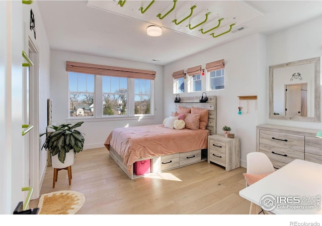 bedroom featuring visible vents, baseboards, and light wood finished floors