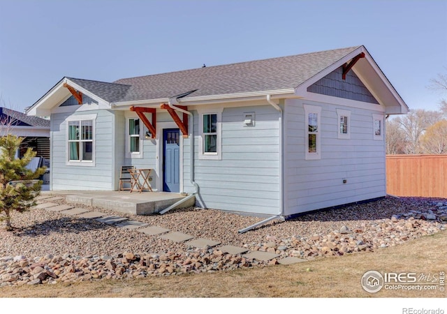 view of front of property with a shingled roof and fence