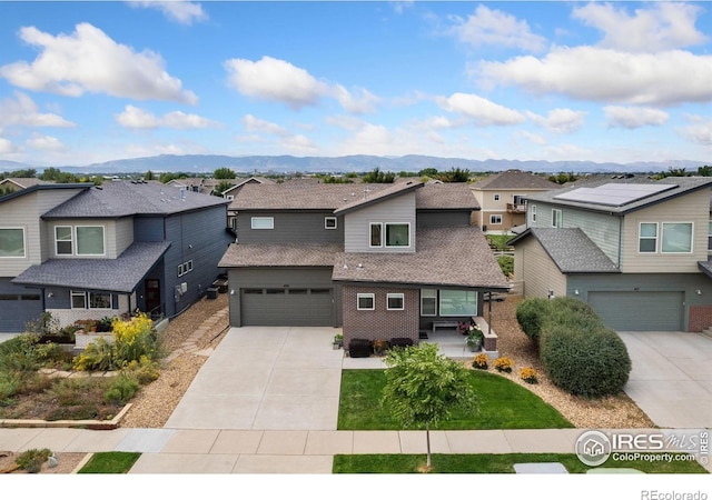 view of front of house with concrete driveway, a mountain view, brick siding, and a residential view