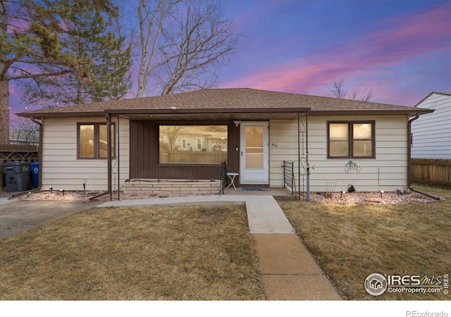 view of front of house with a shingled roof, a front lawn, and fence