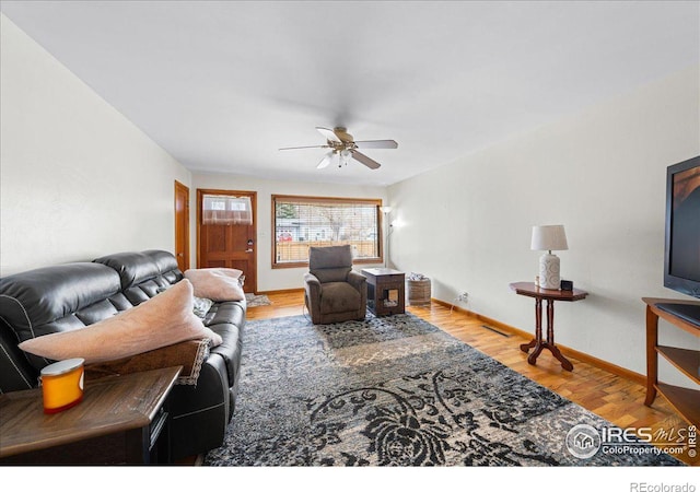 living area featuring visible vents, ceiling fan, baseboards, and wood finished floors