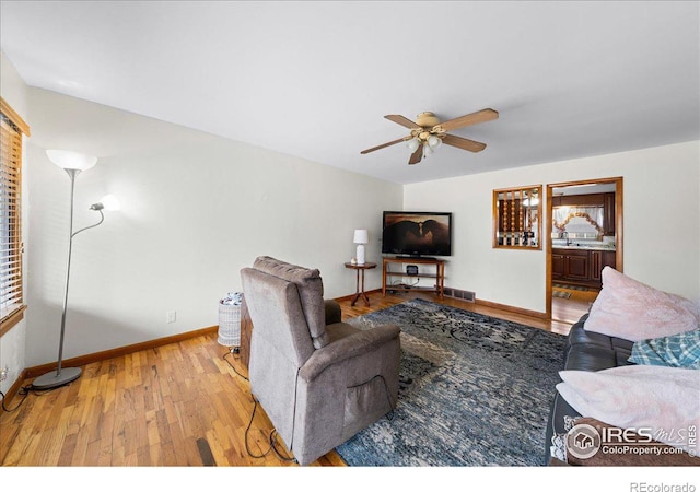 living area featuring visible vents, ceiling fan, baseboards, and wood finished floors