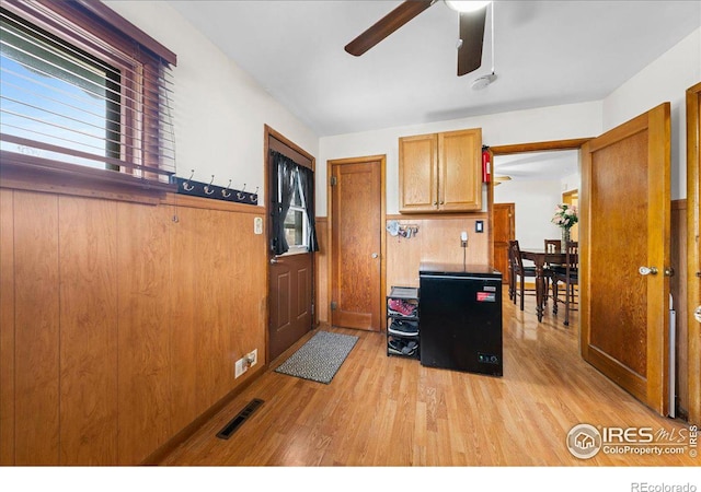 kitchen with visible vents, a wainscoted wall, a ceiling fan, wooden walls, and light wood finished floors