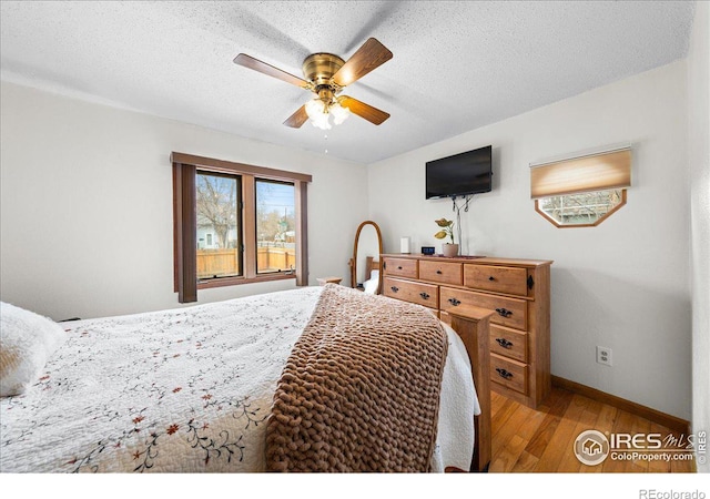 bedroom featuring ceiling fan, a textured ceiling, baseboards, and wood finished floors