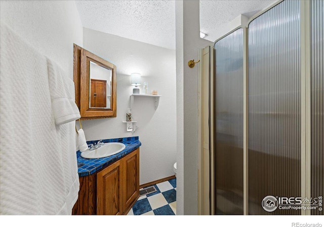 bathroom featuring visible vents, toilet, vanity, tile patterned floors, and a textured ceiling