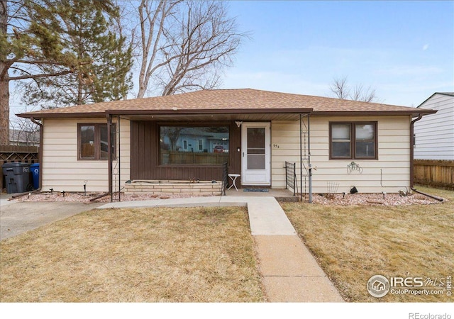 view of front of house featuring roof with shingles, a front yard, and fence