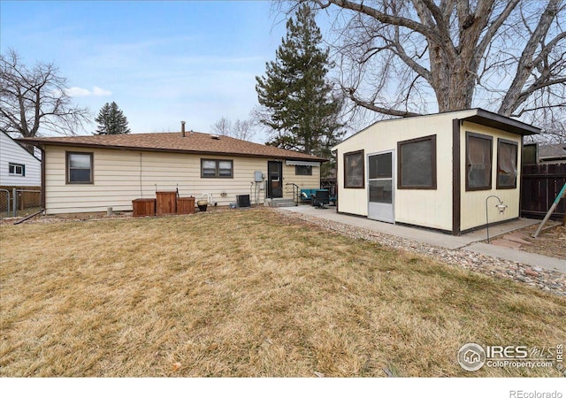 back of property with an outdoor structure, a yard, and fence