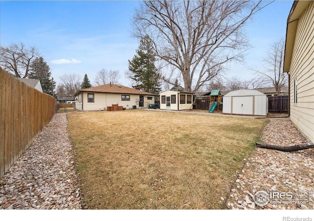 view of yard with an outbuilding, a storage unit, a playground, and a fenced backyard