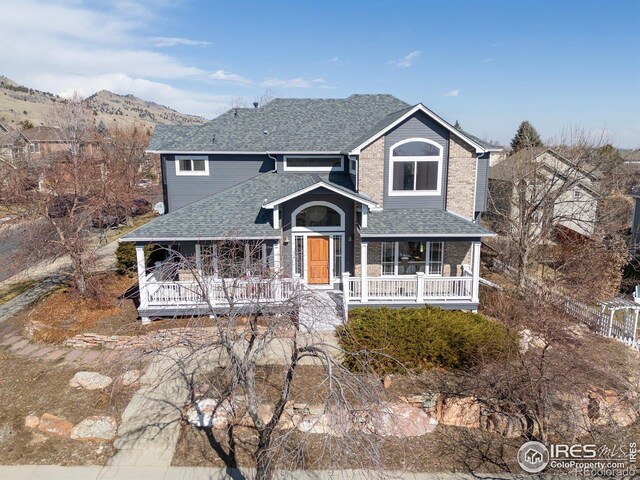 view of front facade featuring a porch, roof with shingles, and a mountain view