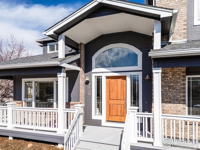 property entrance featuring covered porch and brick siding