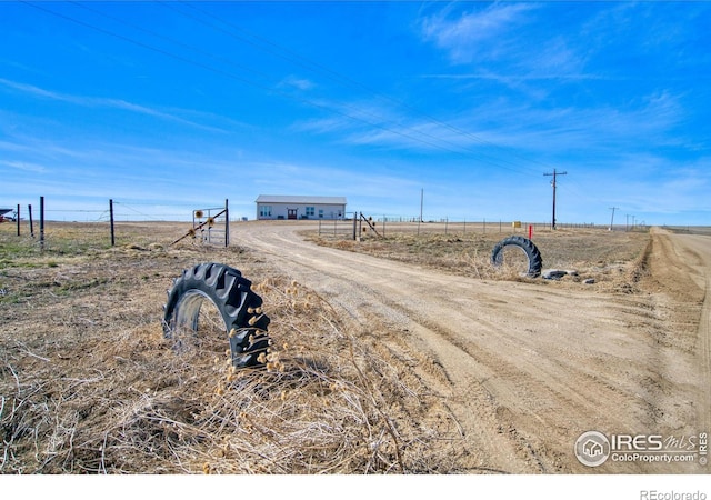 view of street with a rural view and dirt driveway