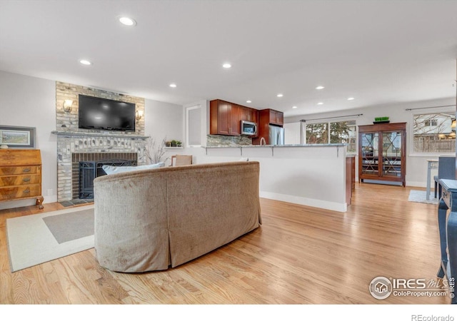 living area with recessed lighting, light wood-type flooring, baseboards, and a fireplace