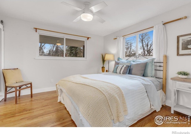 bedroom featuring ceiling fan, baseboards, and light wood-style floors