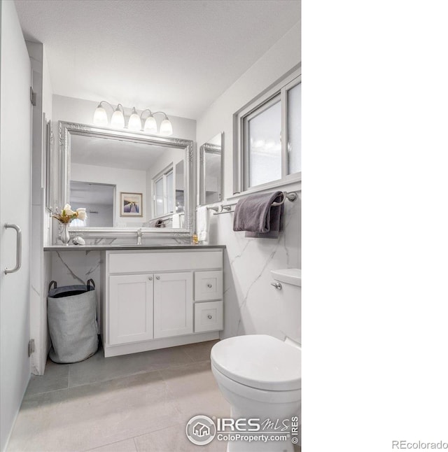 bathroom with tile walls, toilet, and vanity