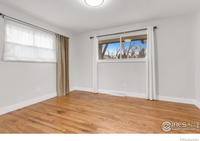 unfurnished room with baseboards, visible vents, and light wood-type flooring