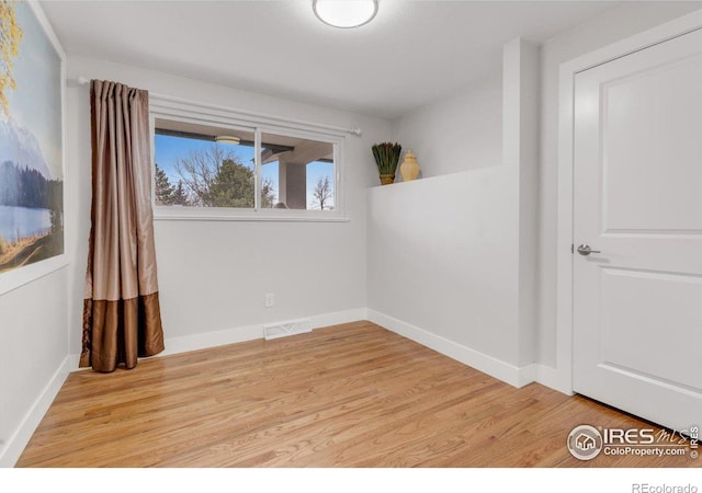 unfurnished room with visible vents, light wood-type flooring, and baseboards