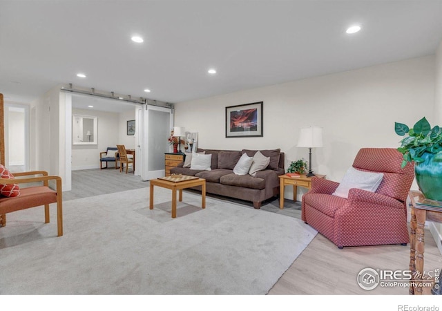 living room featuring recessed lighting, a barn door, and light wood finished floors