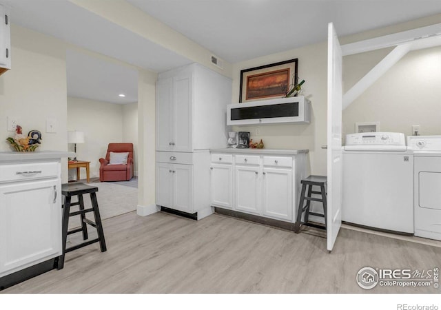 laundry area with light wood-type flooring, visible vents, washing machine and dryer, and laundry area