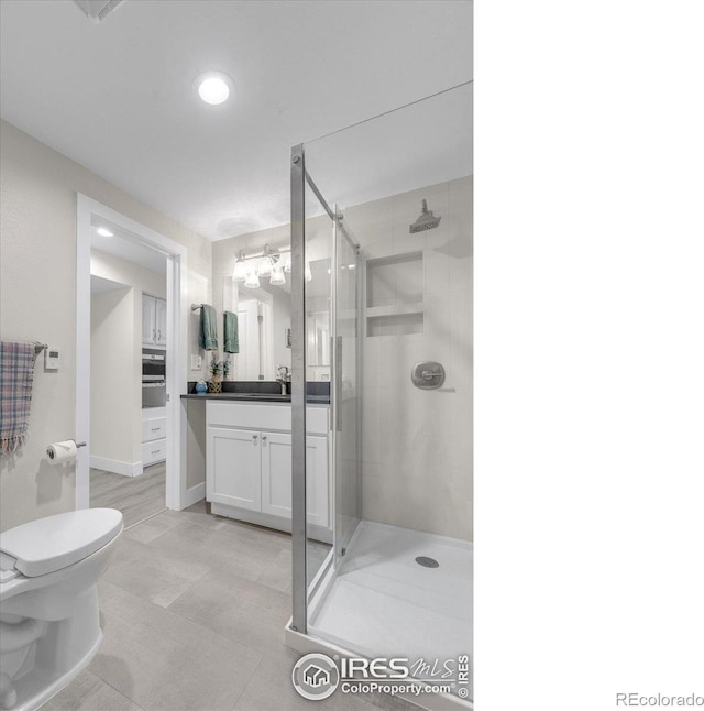 bathroom featuring vanity, a shower stall, and toilet