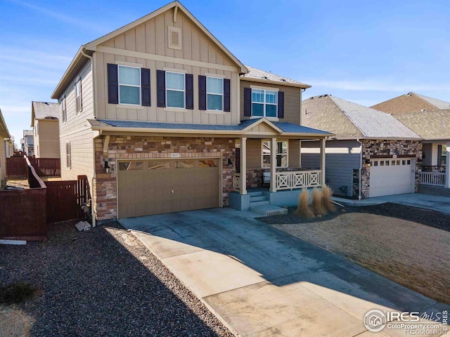 view of front of house featuring stone siding, fence, covered porch, board and batten siding, and concrete driveway