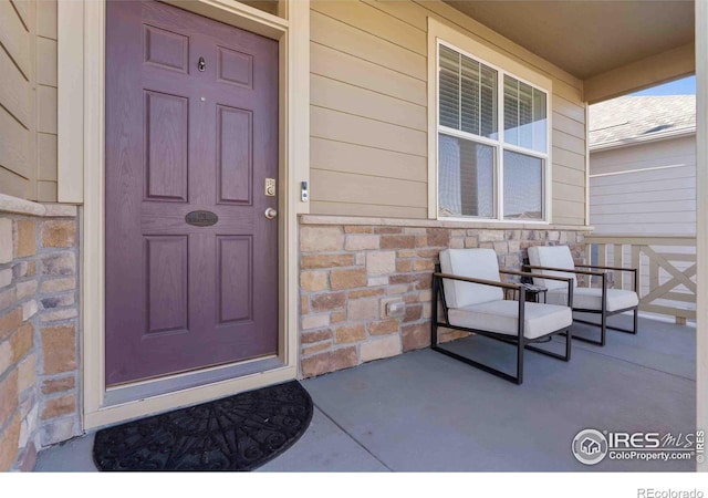 doorway to property featuring covered porch and stone siding