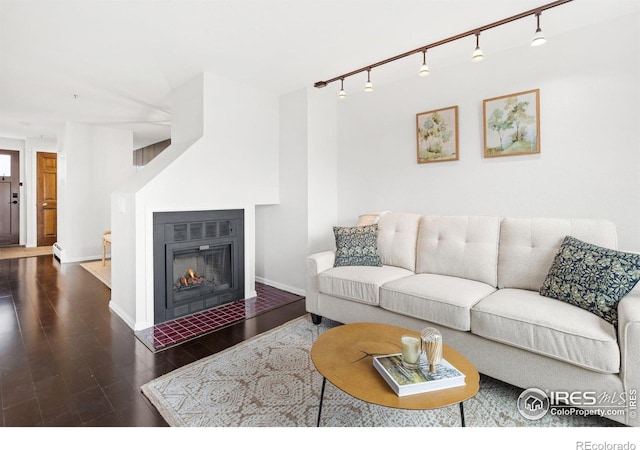 living room featuring a glass covered fireplace, baseboards, and wood finished floors