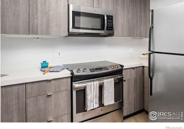 kitchen with appliances with stainless steel finishes, modern cabinets, and light countertops