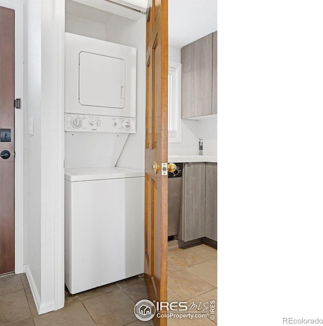 clothes washing area with laundry area, stacked washer / dryer, and light tile patterned floors