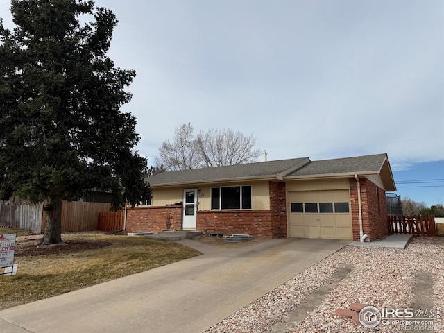 ranch-style home with brick siding, an attached garage, driveway, and fence