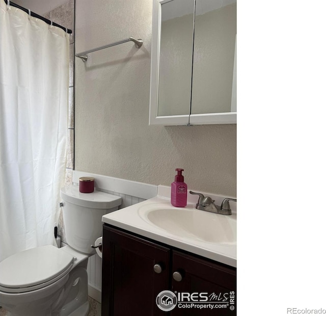 bathroom with toilet, vanity, a shower with shower curtain, and a textured wall