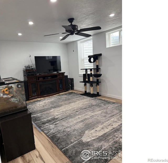 living area with wood finished floors, baseboards, recessed lighting, ceiling fan, and a textured ceiling