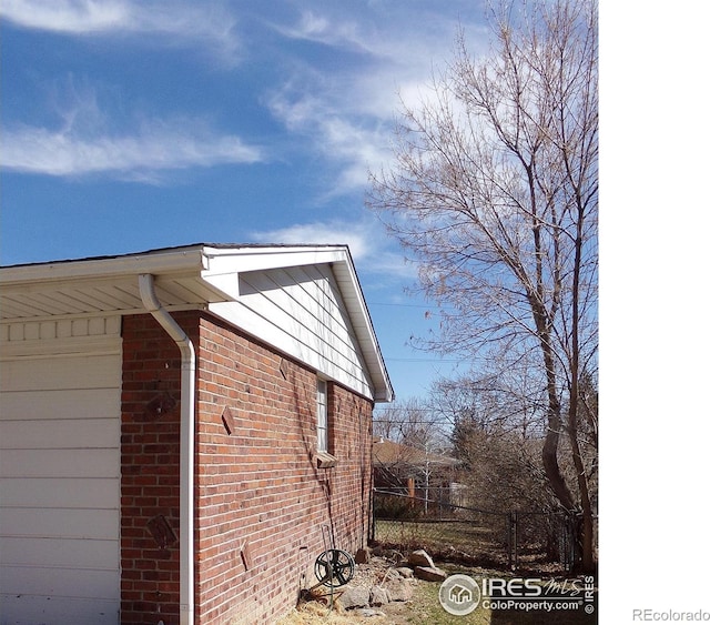 view of side of home with brick siding and fence