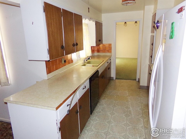 kitchen with light countertops, freestanding refrigerator, black dishwasher, and a sink