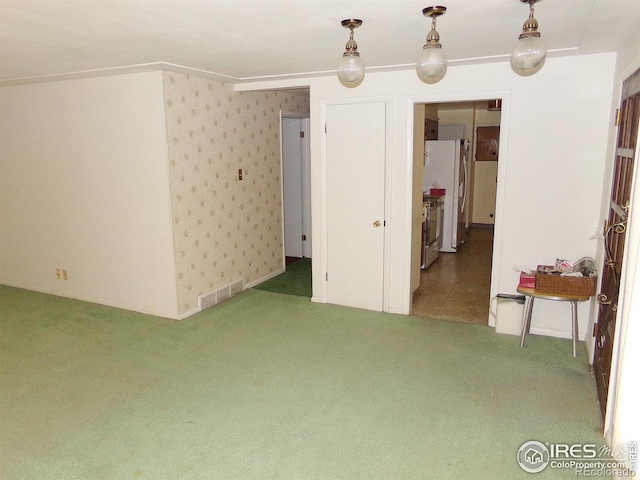 carpeted empty room with visible vents and wallpapered walls