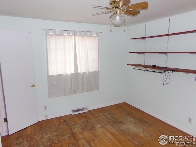 spare room featuring baseboards, wood finished floors, visible vents, and ceiling fan