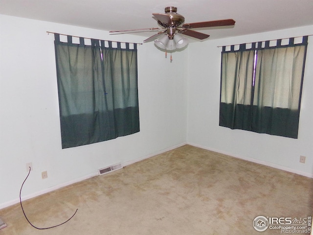 empty room featuring carpet flooring, baseboards, visible vents, and ceiling fan