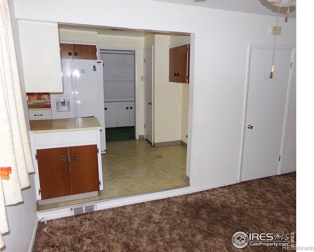 kitchen featuring carpet flooring, white refrigerator with ice dispenser, and visible vents